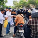 Ketua PWI Riau Raja Isyam membagikan nasi kepada pengendara didepan kantor PWI Riau jalan Arifin Ahmad, Pekanbaru.