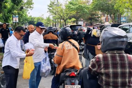 Ketua PWI Riau Raja Isyam membagikan nasi kepada pengendara didepan kantor PWI Riau jalan Arifin Ahmad, Pekanbaru.