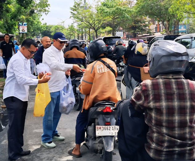 Ketua PWI Riau Raja Isyam membagikan nasi kepada pengendara didepan kantor PWI Riau jalan Arifin Ahmad, Pekanbaru.